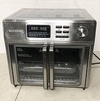 Front view of Kalorik Maxx air fryer oven showing digital control panel, dual glass doors, and stainless steel housing.