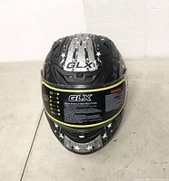 Front view of GLX helmet with star graphics, face shield with instructions and size chart visible
