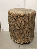 Full view of the solid wooden log stool with bark and flat top surface.