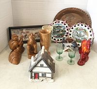 Overview of lot with various figurines, wooden cups, glass goblets, decorative plates, and copper tray.