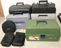 Front view of various empty cases including Old Pal 1090 tackle box, Dremel Trio case, Panasonic round case, and other black cases