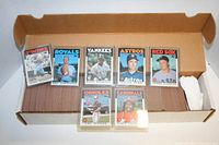 Open box showing stacks of baseball cards with front cards visible including Kirby Puckett (Twins), Bret Saberhagen (Royals), Rickey Henderson (Yankees), Nolan Ryan (Astros), Roger Clemens (Red Sox), Cal Ripken (Orioles), Vince Cole (Cardinals) cards.