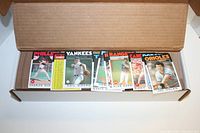Open cardboard box showing a stack of 1986 Topps Baseball cards with several cards from Philadelphia, Yankees, Rangers, and Orioles visible.