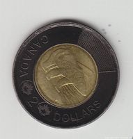 Single 2022 Canadian $2 coin with black outer ring and polar bear design on the inner core, showing signs of use.