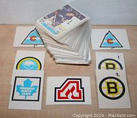 Photo of a large stack of 1977-78 OPC NHL hockey cards with visible card backs showing NHL team logos such as Toronto Maple Leafs, Buffalo Sabres, Colorado Rockies, Boston Bruins, and Hartford Whalers.