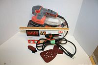 Full view of Black+Decker Mouse Detail Sander with sanding sheets, cord, parts, and original box.