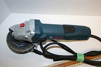 Side view of Bosch handheld grinder showing the body, power cord, and attached abrasive disc.
