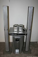 Wide shot showing full set of JVC surround sound system components including two tall speakers, two satellite speakers, DVD player, and subwoofer on a carpeted floor.