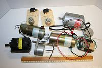 Photo showing seven step down motors of various sizes and two beige Cromag control boxes, on a white background with ruler for scale.