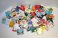 Photo showing a large pile of assorted used matchbook covers with various colorful designs and logos for airlines, hotels, and restaurants.
