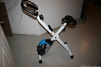 Full view of the ProGear stationary bicycle showing white metal frame with blue housing, adjustable black seat, and black handlebars.