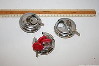 Top view of three chrome disc padlocks with attached keys including red plastic covered keys.