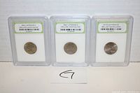 Photo showing front view of three individually slabbed Jefferson nickels from 1963-P, 1964-P, and 2019-D, displayed upright in labeled protective cases.