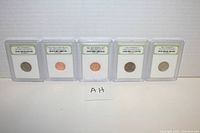 Front view of five slabbed vintage US coins standing upright against a white background.