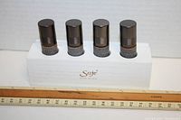 Four amber glass bottles with black caps on white wooden SAJE Natural Wellness stand, position showing side labels