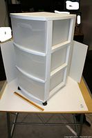 Front angled view showing three deep semi-transparent drawers and white plastic frame on small caster wheels.