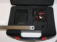 TENS 3000 unit and leads placed inside original molded plastic foam cutout case, measuring approx 5.5 inches.