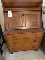 Front view of the antique solid wood desk showing drop-front panel and three drawers with wooden knobs.