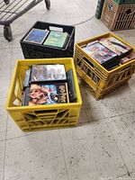 Three crates filled with various DVDs, mostly in plastic cases with printed covers.