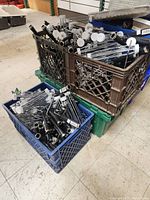 Three crates filled with multiple paint roller frames with black handles and metal frames piled inside, seen from above and side.
