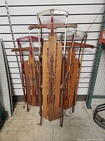 Photo showing three Flexible Flyer sleds leaning against a slat wall, two 50 inches long and one 62 inches long.
