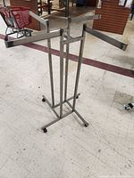 Full view of the metal 4-arm clothing rack showing adjustable arms and height.