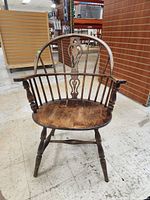Front view of antique Windsor style wooden chair showing curved backrest and carved central splat.