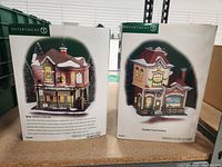 Photo of two Department 56 collectible Christmas village boxes, featuring Molly O'Brien's Irish Pub and Paradise Travel Company buildings.