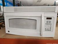 White GE mountable microwave oven front view showing door and handle.