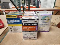 Photo showing two boxes of SpeedFinish patching and finishing compound and five boxes of Polyblend Non-Sanded Grout placed on a shelf.