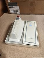 Top view of boxed Kenmore handheld hand mixer, showing the white mixer unit seated in its box with speed settings visible.