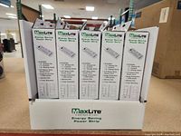 Front view of MaxLite Energy Saving Power Strips box showing 10 individual boxed units inside with branding and features.