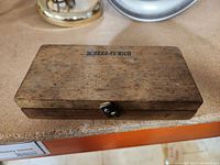 Closed wooden case with Scherr-Tumico stamp on the lid showing external appearance and latch.