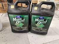 Two brand new jugs of Lilly Miller Moss Out! moss killer concentrate for lawns on a white surface, showing their front labels and product information.