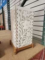 Side view of a 14-inch tall rectangular paper lamp with a floral pattern and wooden base on a table.