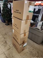 Four stacked cardboard boxes labeled fragile, containing the track lights unopened.