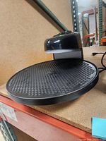 Front angle view of Presto Pizzazz Plus rotating pizza oven showing non-stick cooking tray and upper heating element housing.