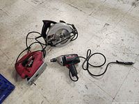 Photo of Craftsman drill, Skil jigsaw, and circular saw on floor showing overall condition and cord attachments