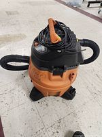 Front view of the orange and black Ridgid shop vacuum with hose and power cord wrapped.