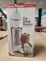 Front view of boxed Hamilton Beach The Drink Master drink mixer showing product and packaging details.