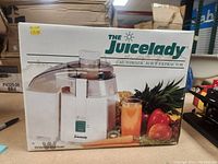 Front side of the box showing the Juicelady Automatic Juice Extractor with fruits and a glass of juice. Price sticker on top left corner.