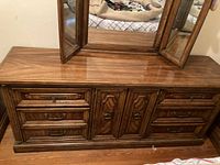 Front view of oak dresser with large mirror showing detailed wood grain, central cabinet doors, drawers with ornate brass handles.