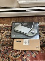 Top-down image of Tech Lapdesk and Dell computer screen boxes on patterned carpet