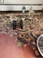Five animal figurines arranged on a patterned rug including composed blown glass birds, dolphin and tiger, and polished black onyx bulls.