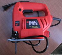 Photo showing the full side profile of the red Black & Decker sabre saw with variable speed label and power cord visible.