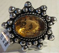 Close-up image of the ring face showing the oval citrine gemstone set in an ornamental German Silver bezel with rounded silver bead details.