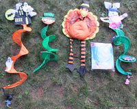Set of five holiday-themed wind spinners laid out on grass showing all five with visible spirals and themed characters.