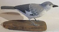 Side profile view of hand carved and painted wooden Mockingbird mounted on wooden base