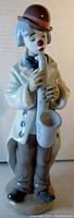 Front view of the Lladro clown figurine playing a saxophone showing the front details including the brown hat, white coat, and saxophone.