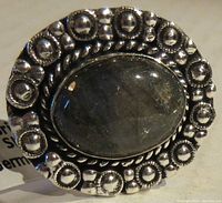 Close-up photo of oval labradorite gemstone ring with detailed German silver bezel showing bead and circular raised elements.